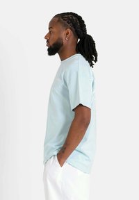 Camiseta de algodón de gran tamaño en azul claro con mangas cortas, que presenta un cuello redondo y detalles bordados en la parte delantera.