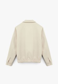 Lichtbeige jasje met een gladde stofstructuur, kraag en gathered zoom. Heeft knoopsluiting aan de manchetten en een ontspannen silhouet. Achteraanzicht.