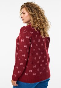 Maglione a maglia bordeaux con strisce verticali bianche, scollo rotondo, polsini e orlo ribattuti, caratterizzato da una texture morbida e una vestibilità rilassata.