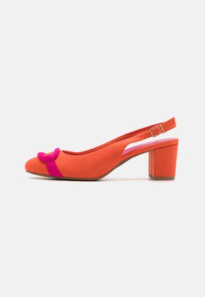 Pomarańczowy zamszowy but typu slingback na szerokim obcasie, z regulowanym paskiem na klamrę i ozdobną jasnoróżową kokardą z przodu.