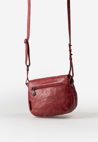 Rote Leder Umhängetasche mit strukturierter Oberfläche, verstellbarem Gurt und einer Reißverschluss-Vordertasche. Die Form ist ein kompaktes rechteckiges Design.