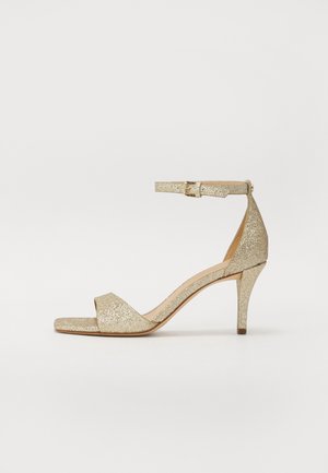Gylne glitrende høyhælede sandaler med ankelstropp, åpen tå og firkantet forparti. Har en slank, avsmalnet hæl for heving.