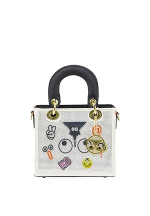 Petit sac à main blanc avec une poignée noire, décoré d'yeux de dessin animé, d'un signe de paix, d'un smiley et de patches colorés. Porte-clés doré attaché.