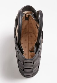 Sac à main noir avec un extérieur tissé, dotée de deux poignées rondes et d'une fermeture éclair. L'intérieur est doublé d'un motif beige.