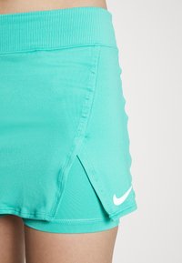 Turkoosinväriset urheilushortsit, joissa on ribattu vyötärö, sivuhalkiot ja valkoinen Nike-tikkauslogo. Valmistettu sileästä, joustavasta kankaasta.