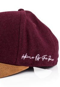 Cappello bordeaux con visiera in suede marrone; presenta il testo ricamato bianco "Home Of The Game" sul lato; tessuto testurizzato.
