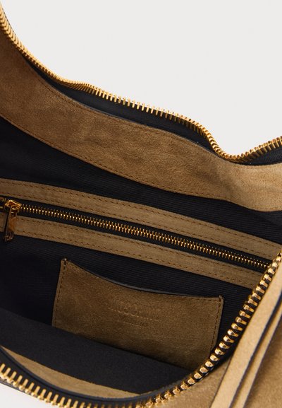 Intérieur de sac en daim beige ouvert avec doublure en tissu noir et poche zippée dorée.