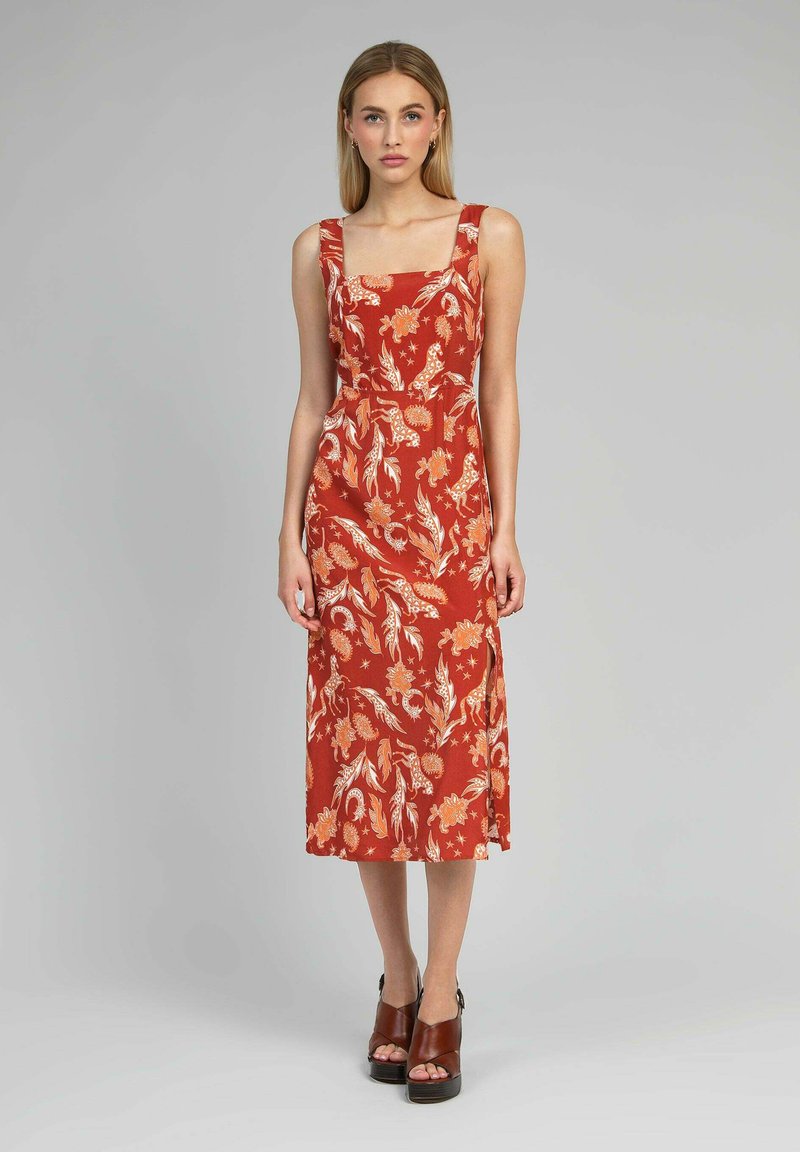 Robe maxi rouge à fleurs avec encolure carrée et larges bretelles. Présente une taille ajustée, une jupe fluide et une fente sur le côté. Talons plateformes marron inclus.