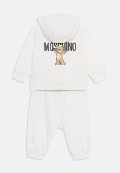Chándal blanco de algodón que presenta una chaqueta con capucha con un gráfico de oso y el texto "Moschino", combinado con pantalones elásticos a juego.