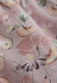 Bomullstyg med ett blommönster i rosa, gult och grönt, med en mjuk textur och subtila detaljer i designen.