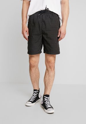 Svarte shorts med hvite pinstriper, elastisk talje og snor. Bæret med svarte høye sneakers med grafiske detaljer.