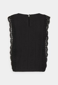 Haut noir avec des bordures en dentelle le long des épaules, tissu texturé avec des rayures verticales, et une petite ouverture en forme de clé à l'arrière.