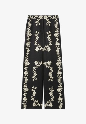 Pantalones negros de pierna ancha con bordado floral blanco intrincado a lo largo de los lados y la cintura, hechos de tela ligera.