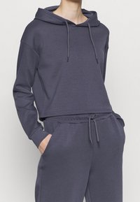 Gray cropped hoodie with drawstrings, soft fabric, long sleeves, and a relaxed fit, paired with matching drawstring joggers.