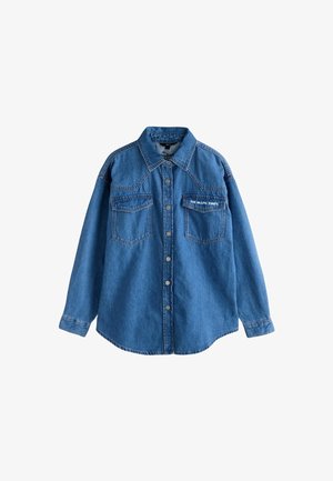 Denimskjorta i ljusblått, med knappar fram, två bröstfickor och texten "The Rolling Stones" broderad i vitt.