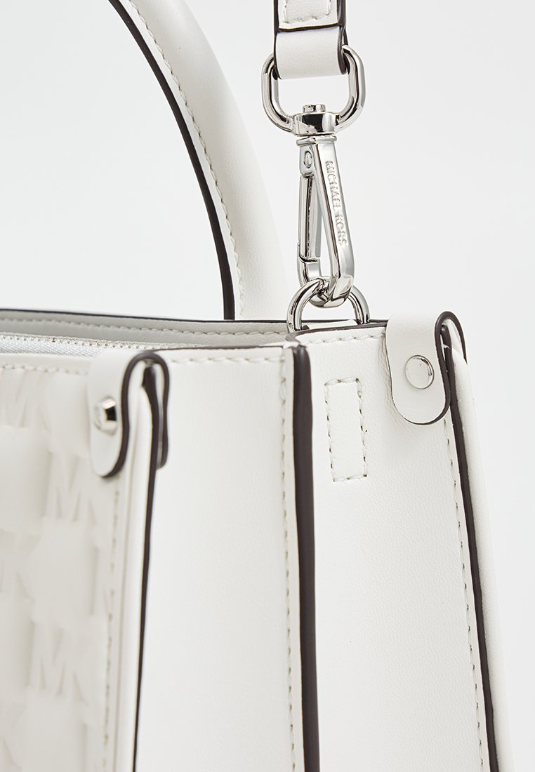 Weißes Lederhandtasche mit schwarzen Akzenten, strukturierte Form, silberne Beschläge und eine seitliche Logo-Musterfläche mit einem Reißverschluss und verstellbarem Trageriemen.