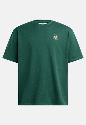 Green cotton t-shirt with a round neck and short sleeves. Features a small circular graphic with the text "THE WORLD IS MINTING."