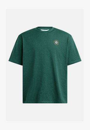 Groene katoenen t-shirt met een ronde hals en korte mouwen. Bevat een kleine ronde afbeelding met de tekst "DE WERELD MUNT."
