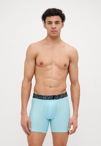 Hellblauer Boxerbriefs mit einem schwarzen "UNDER ARMOUR"-Bund, ausgestattet mit einem figurbetonten Design und glatter Textur. Die Vorderseite hat eine konturierte Tasche.