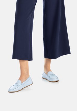Mocassins en cuir bleu clair avec des accents cousus, portés avec un pantalon large bleu marine. Les chaussures présentent un profil bas et une texture lisse.