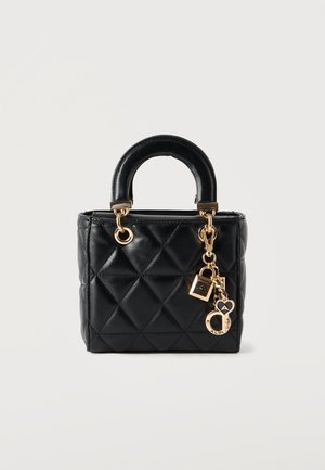 Schwarze gesteppte Handtasche mit rundem Griff, goldfarbener Hardware und dekorativen goldenen Anhängern, die am Griffring befestigt sind.