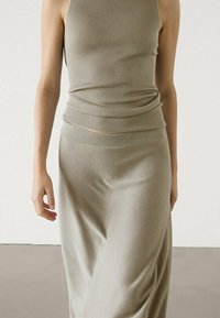 Khaki geribbelde tanktop gecombineerd met een vloerlange rok, met een gladde textuur en een aansluitende silhoutte, wat zorgt voor een naadloze flow.