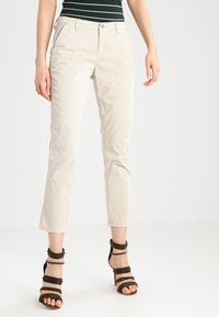 Beige chinos med en skräddarsydd passform, med sidofickor, knappstängning fram och uppvikta fållar. Matchas med mörkgröna sandaletter.