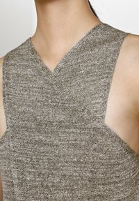 Haut marron sans manches avec un col en V, un tissu texturé et une silhouette ajustée avec des côtés découpés.