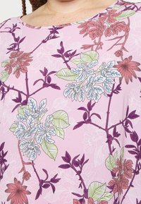 Růžový květinový top s vzorem fialových, zelených a červených květů a listů, vyrobený z lehkého materiálu s jemnou texturou.