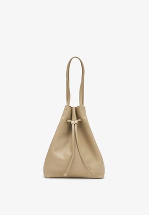 Bolso cubo de cuero beige con cierre de cordón y correa larga para el hombro, de pie sobre fondo blanco.