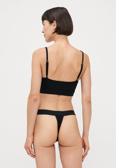Black fabric bralette with adjustable straps and a seamless design, paired with a matching thong featuring a narrow waistband.