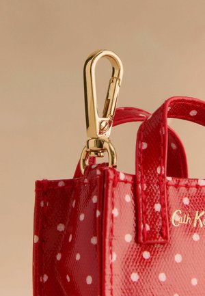 Rote Lackleder-Handtasche mit weißen Punkten, ausgestattet mit goldenen Clips und kleinen Griffen zum Tragen oder Befestigen.