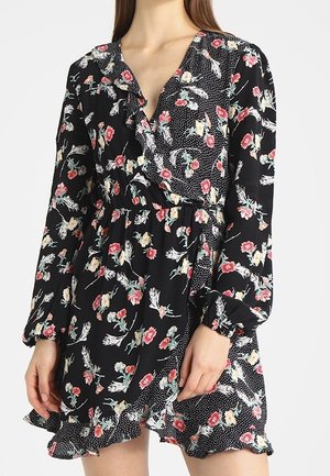 Vestido negro con flores, de manga larga, escote en V, con volante en el dobladillo y un patrón de lunares en el borde. Presenta un estampado floral colorido sobre un fondo oscuro.