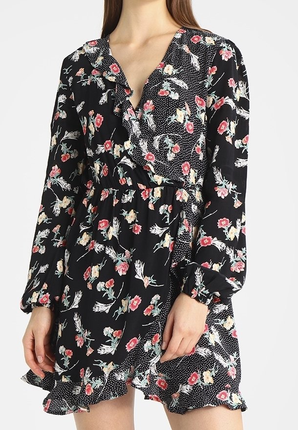 Černé květinové šaty s dlouhými rukávy, výstřihem do V, volány a puntíkovaným vzorem na spodním lemu. Obsahují barevný květinový potisk na tmavém pozadí.