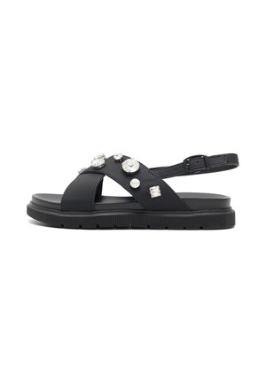 Sort flad sandal med krydsede remme dekoreret med forskellige klare sten og en justerbar ankelrem med spænde.