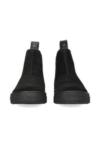 Stivaletti neri in suede con pannelli elastici laterali, suola in gomma testurizzata e una piccola linguetta con marchio sul retro.