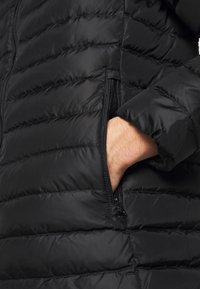 Černá prošívaná péřová bunda s boční kapsou na zip a elastickými manžetami, vyrobená z hladkého, voděodolného materiálu.