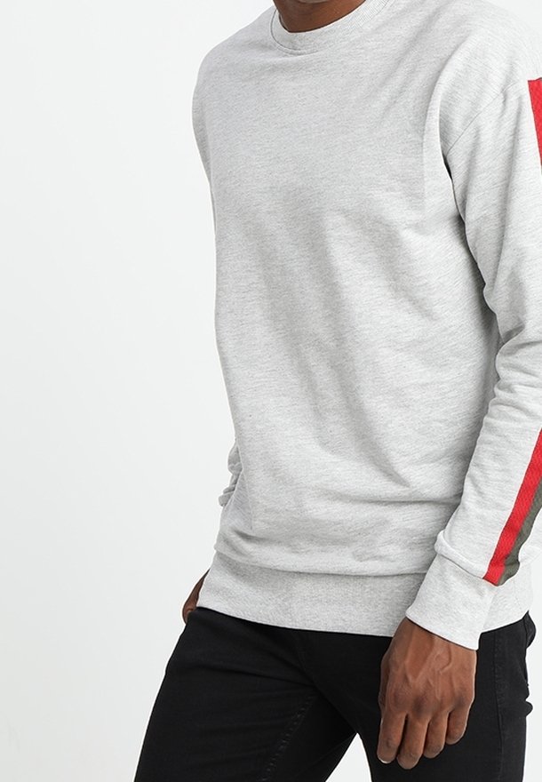 Sudadera gris de manga larga, con cuello redondo y rayas contrastantes rojas y verdes en la manga derecha. Textura de tela suave.