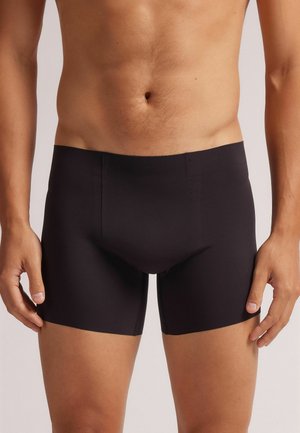 Boxers ajustados negros hechos de tejido suave, con una cintura sin costuras y un diseño ceñido que se adapta al cuerpo.