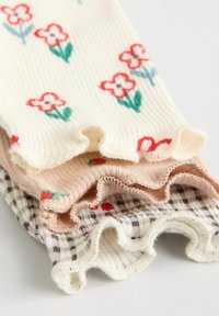 Kreminių, rožinių ir languotų raštų raišteliai; turi gėlių siuvinėjimą ir raukšlėtus kraštus, suteikiančius tekstūros.