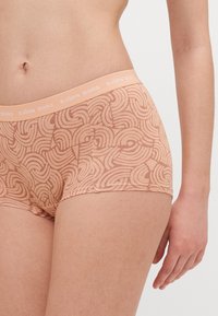 Világos őszibarack színű, mintás boxer alsónadrág, puha elasztikus derékpánttal, amelyen a "BJÖRN BORG" márkaneve szerepel. A minta hullámvonalakból áll.