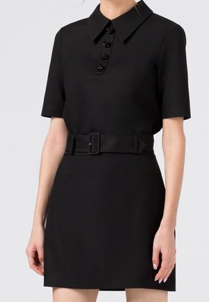 Robe noire à manches courtes avec un col pointu, quatre boutons décoratifs sur la poitrine et une large ceinture à boucle rectangulaire.