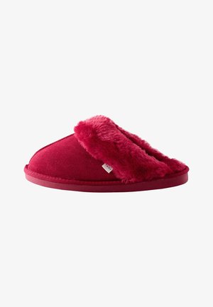 Rode instap pantoffel met zachte, pluizige voering en buitenrand, met platte zool en een klein stoffen label aan de zijkant.