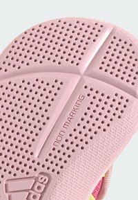 Gumová podrážka v světle růžové barvě s kulatými perforacemi, texturovanými vzory pro dobrou přilnavost a embosovaným textem "neznačící" pro zvýšení trakce.