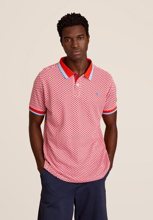 Polo shirt à motif rouge avec un col et des poignets contrastés, présentant des accents bleus. Manches courtes, coupe décontractée et forme d'ourlet arrondi.
