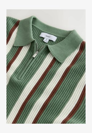 Grøn ribstrikket polo med lynlås i nakken, der har skiftevis striber i creme og rust. Blød tekstur og struktureret kravedetalje.