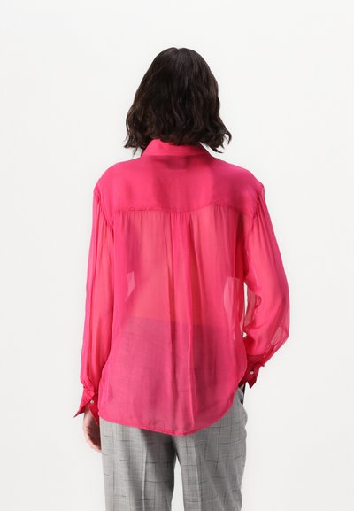 Blouse rose clair à manches longues et translucides, avec un col et des détails froncés dans le dos. Boutons aux poignets et coupe décontractée.