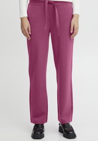 Fuchsia wide-leg trousers with a drawstring waist and smooth texture, paired with black platform shoes.