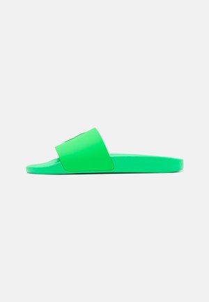 Sandale mule verte avec une large bride et une semelle texturée, fabriquée en caoutchouc lisse avec un design plat.