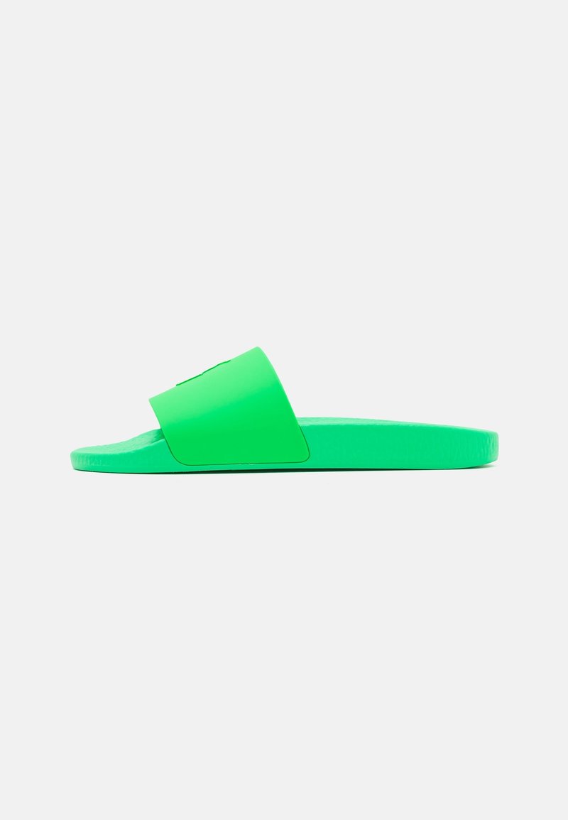 Sandale mule verte avec une large bride et une semelle texturée, fabriquée en caoutchouc lisse avec un design plat.